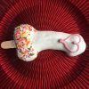 White chocolate dipped penis cookie with sprinkles and a heart decoration